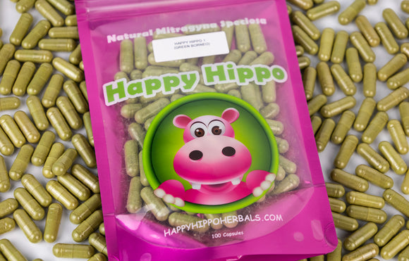 Featured Image depicting a packet of Happy Hippo brand kratom capsules. The package sits on top of a pile of loose kratom capsules filled with kratom powder.