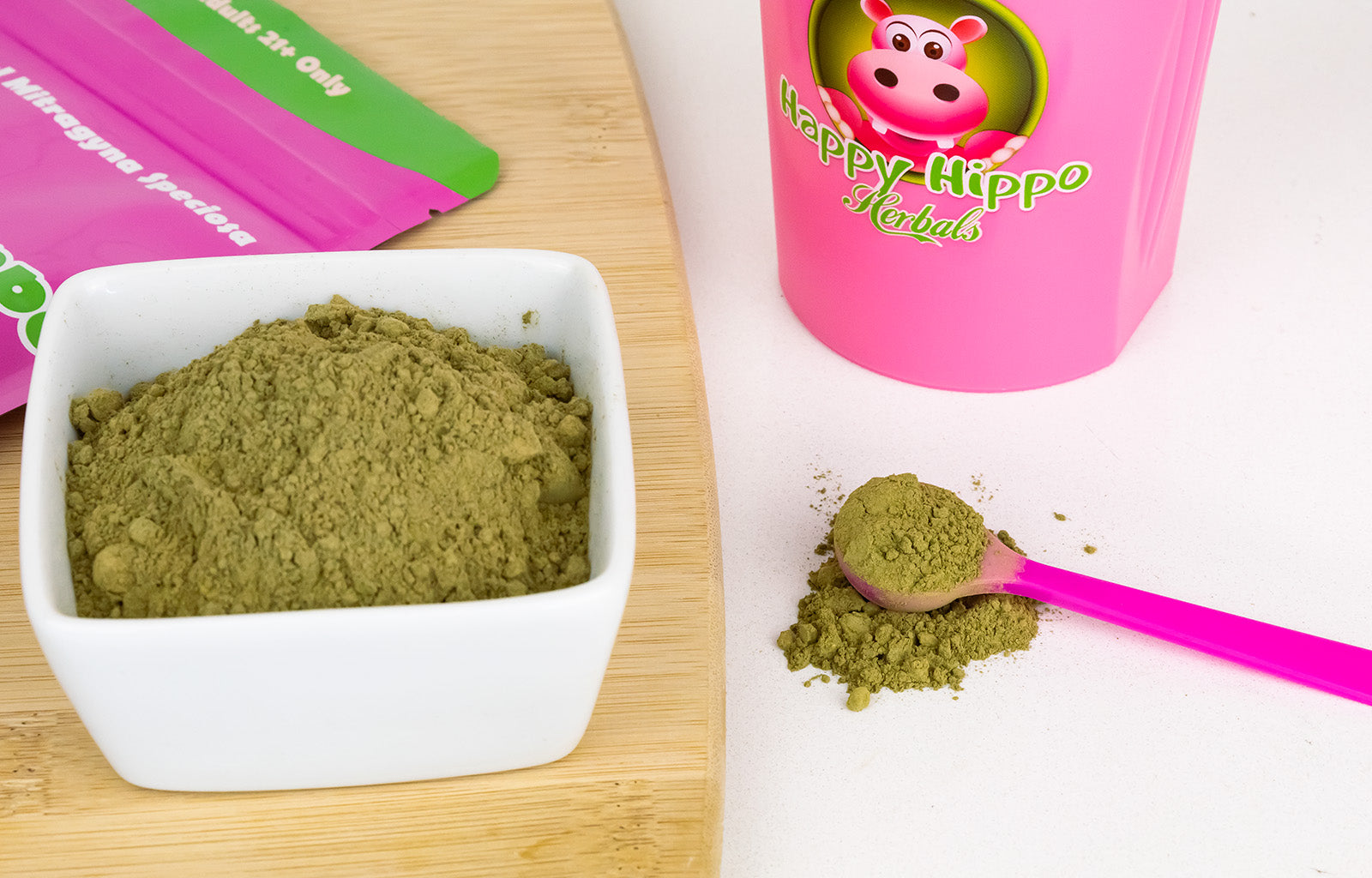 Featured image depicting a large bowl of Green Malay Kratom Powder, next to which sits a 1-gram little pink measuring scoop, and a Happy Hippo brand smoothie shaker.