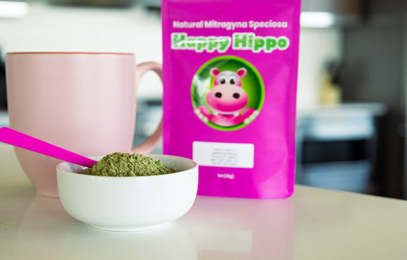 Featured image depicting a Happy Hippo branded packet of Malay Kratom sitting on a kitchen counter. A pink kratom tea cup, and a bowl of loose Malay Kratom Powder sits in the foreground.